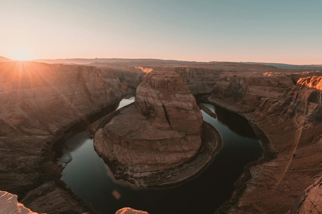 The sun is setting over a canyon with a lake
